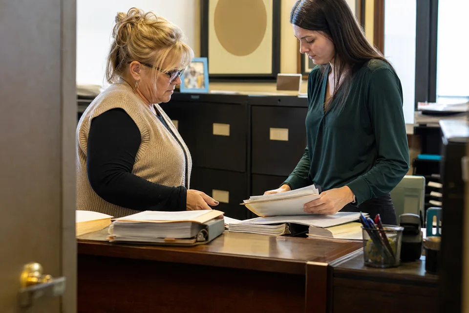City clerk and a purchasing agent reviewing signed vendor agreements at the counter of a city hall office